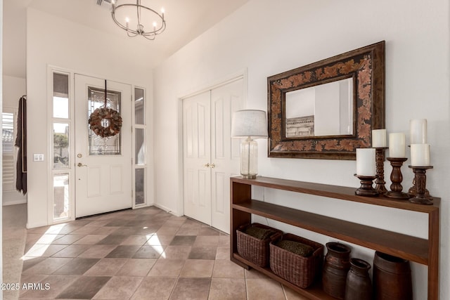 tiled entrance foyer featuring a notable chandelier and lofted ceiling