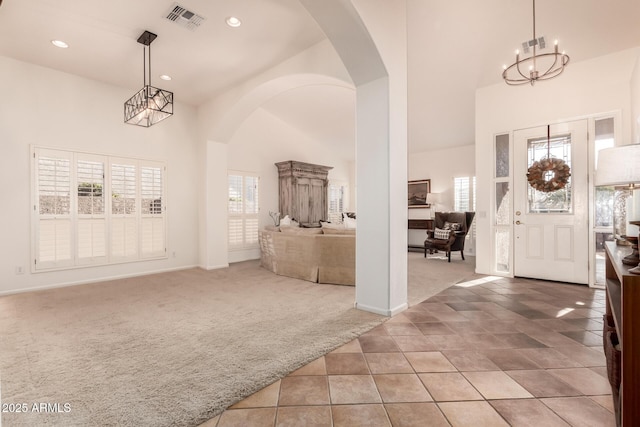 carpeted entrance foyer with a chandelier, a high ceiling, and a wealth of natural light