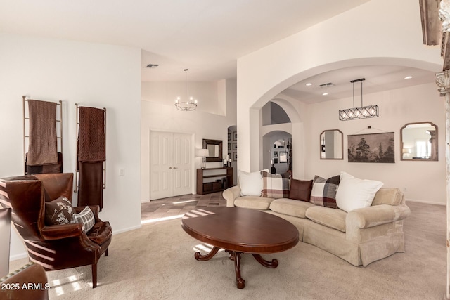 living room with a chandelier, a towering ceiling, and light colored carpet