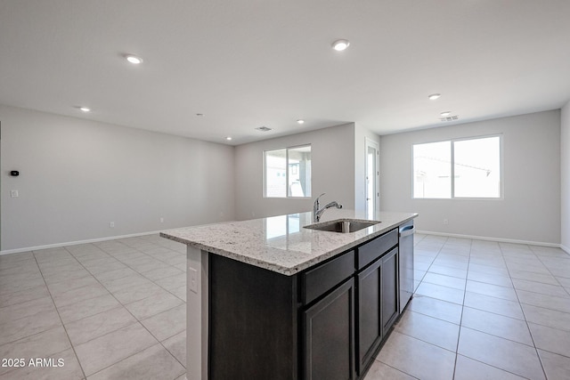 kitchen featuring a sink, open floor plan, light stone countertops, stainless steel dishwasher, and light tile patterned flooring