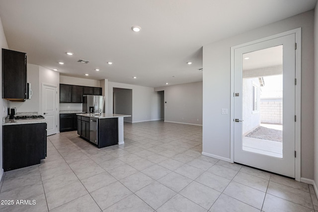 kitchen featuring recessed lighting, open floor plan, light countertops, stainless steel refrigerator with ice dispenser, and a kitchen island with sink