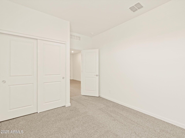 unfurnished bedroom with light colored carpet and a closet