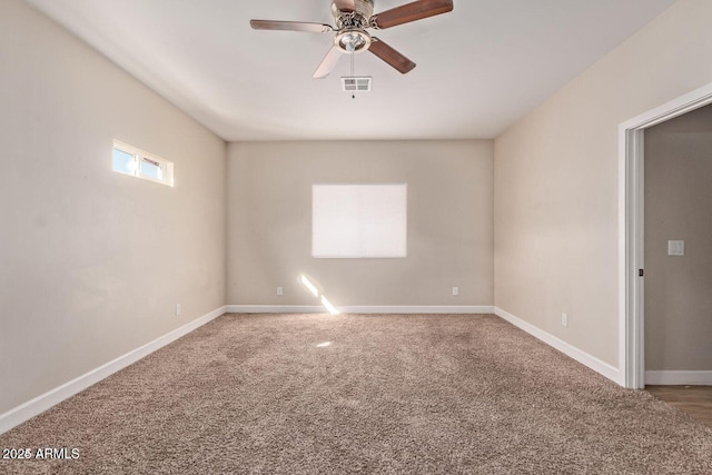 carpeted spare room featuring ceiling fan, visible vents, and baseboards