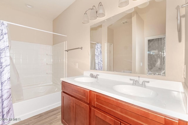 bathroom featuring wood finished floors, double vanity, shower / tub combo, and a sink