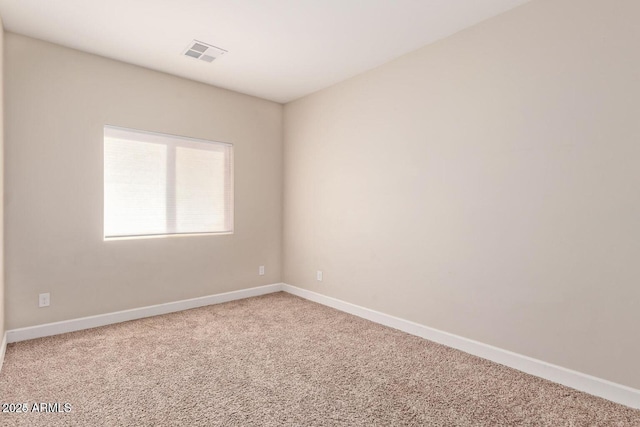 carpeted spare room with visible vents and baseboards