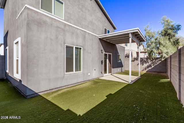 rear view of property featuring a patio area, a fenced backyard, a lawn, and stucco siding