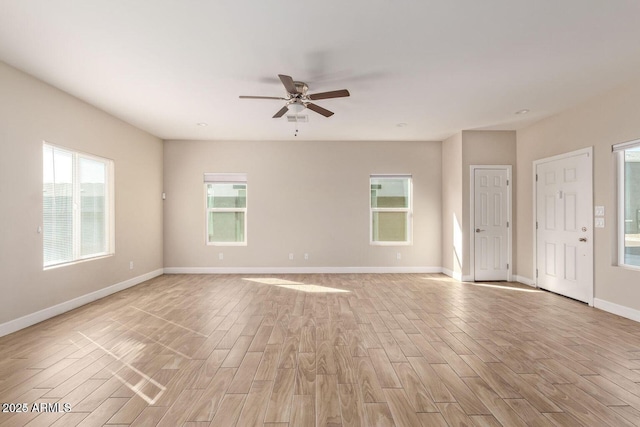 empty room featuring a ceiling fan, baseboards, and light wood finished floors