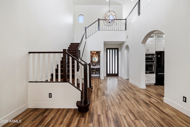 foyer with stairway, baseboards, arched walkways, and a notable chandelier