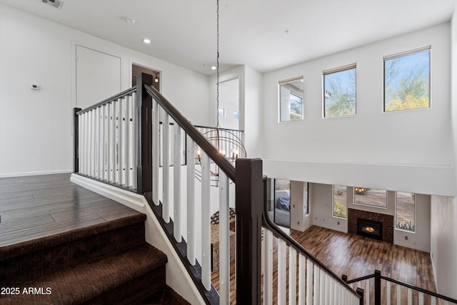 stairs featuring visible vents, wood finished floors, baseboards, recessed lighting, and a tile fireplace