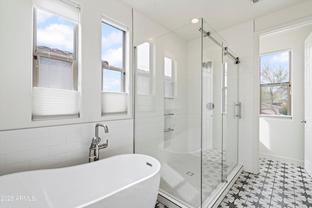 full bathroom with a freestanding tub, tile patterned floors, tile walls, and a shower stall