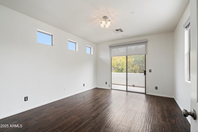 empty room featuring baseboards, dark wood finished floors, and visible vents