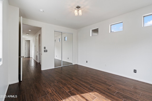 interior space with baseboards, a closet, and dark wood-type flooring