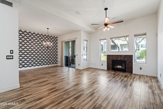 unfurnished living room with ceiling fan, a tiled fireplace, baseboards, wood finished floors, and visible vents