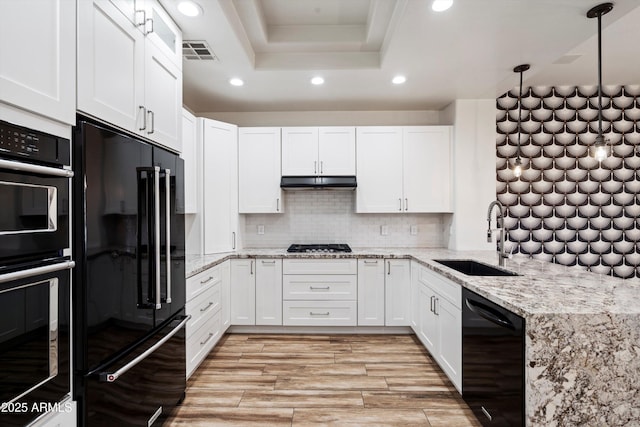 kitchen featuring white cabinets, a sink, recessed lighting, a tray ceiling, and black appliances