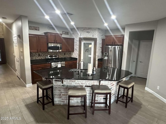28306 N 25th Dl, Phoenix, AZ 85085 - kitchen featuring appliances with stainless steel finishes, a breakfast bar area, decorative backsplash, and light wood-type flooring