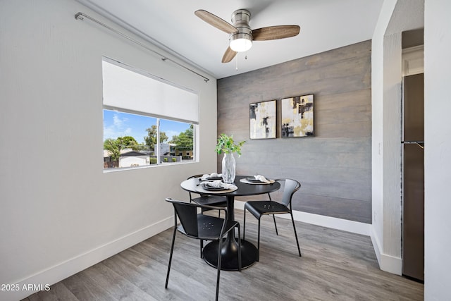 616 S Hardy Dr Unit 203, Tempe, AZ 85281 - dining room featuring a ceiling fan, wood finished floors, an accent wall, and wooden walls