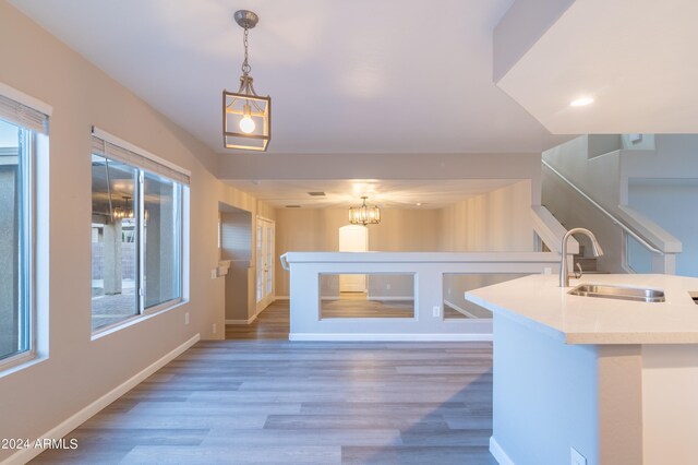 kitchen featuring a kitchen island with sink, sink, decorative light fixtures, an inviting chandelier, and dark hardwood / wood-style floors