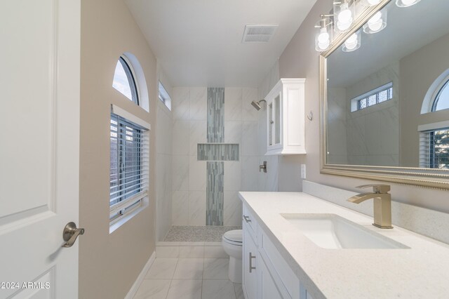 bathroom with vanity, toilet, and tiled shower