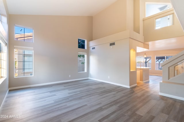 unfurnished living room featuring high vaulted ceiling, a wealth of natural light, and dark wood-type flooring