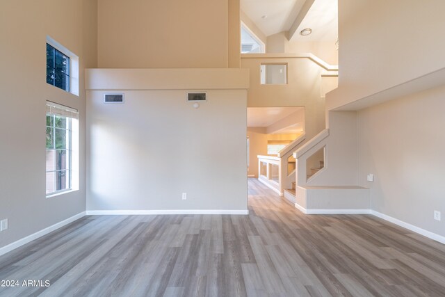 unfurnished living room with light hardwood / wood-style floors and high vaulted ceiling