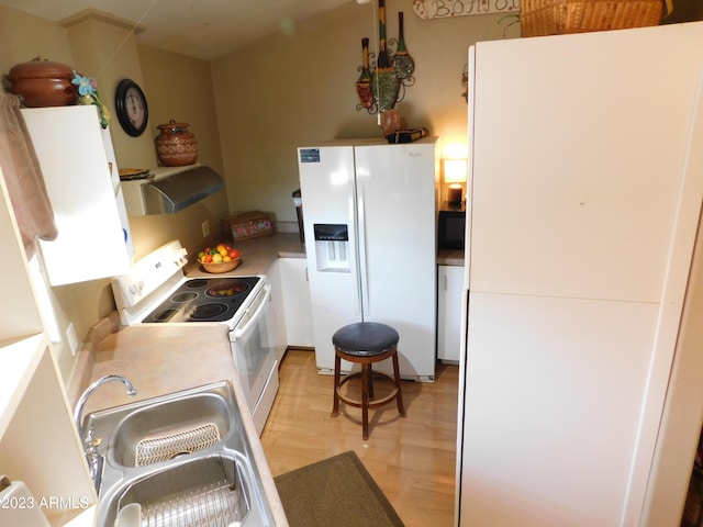 kitchen with a sink, ventilation hood, white appliances, light wood-style floors, and light countertops