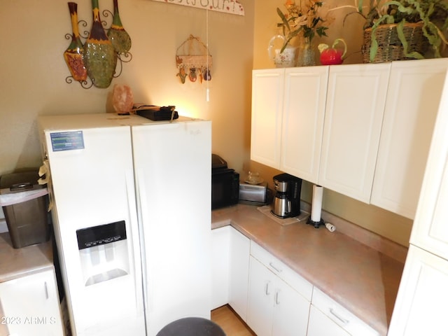 kitchen featuring white cabinetry, light countertops, and white fridge with ice dispenser