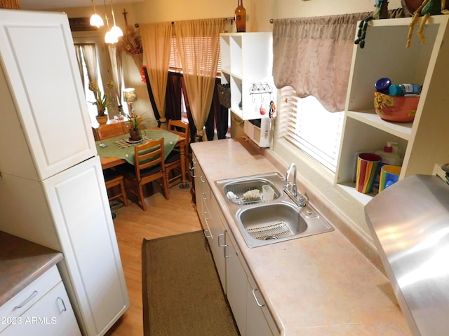 kitchen featuring white cabinetry, light countertops, light wood finished floors, and a sink