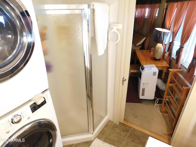 bathroom with a shower stall and stacked washer and clothes dryer