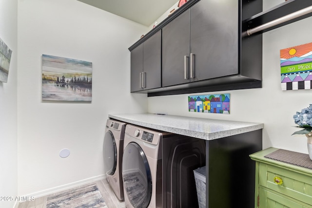 clothes washing area featuring cabinet space, baseboards, light wood-style floors, and independent washer and dryer