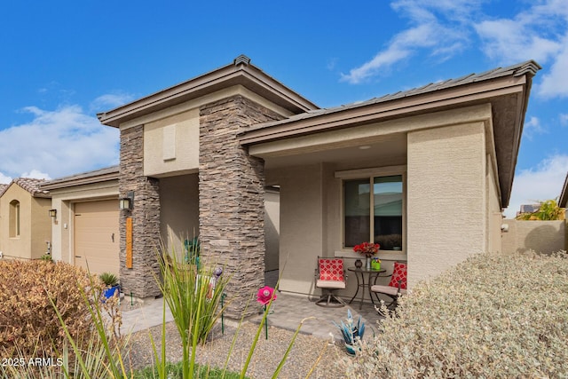 view of front of home featuring a garage, stone siding, and stucco siding