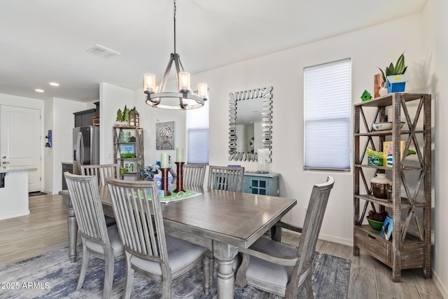 dining area with wood finished floors, visible vents, baseboards, and an inviting chandelier