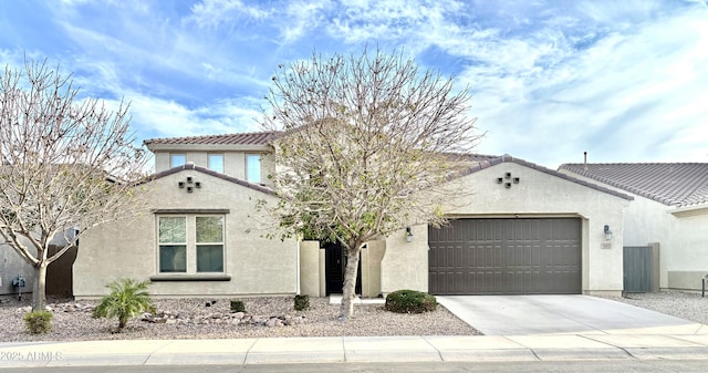 mediterranean / spanish-style home with concrete driveway, an attached garage, a tile roof, and stucco siding