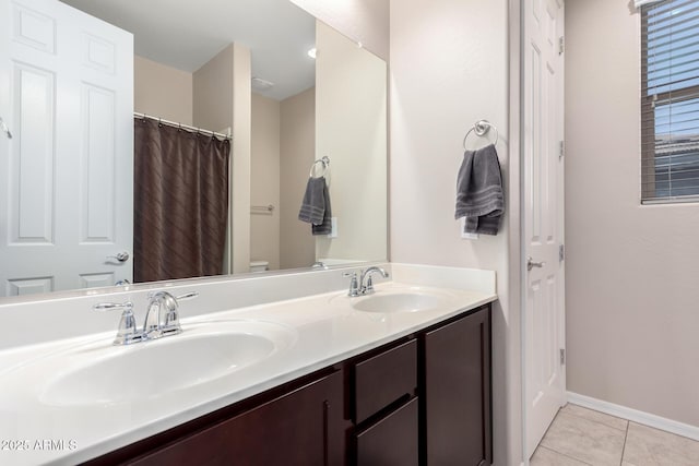 bathroom featuring tile patterned floors, double vanity, baseboards, and a sink