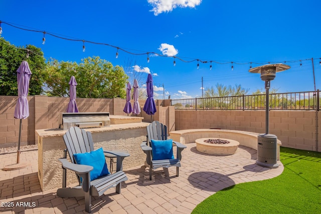 view of patio featuring exterior kitchen, a fire pit, and a fenced backyard