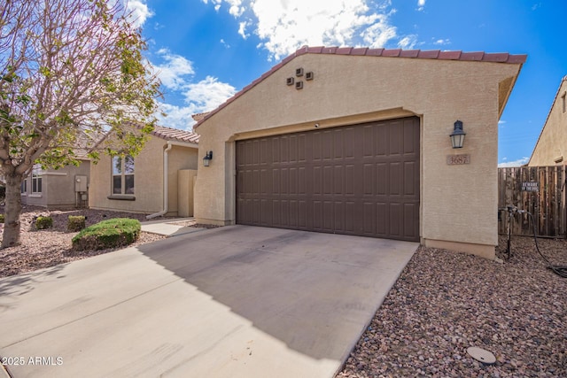 view of front facade featuring fence, stucco siding, concrete driveway, a garage, and a tile roof