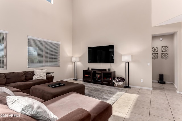 living room featuring light tile patterned floors, baseboards, and a towering ceiling