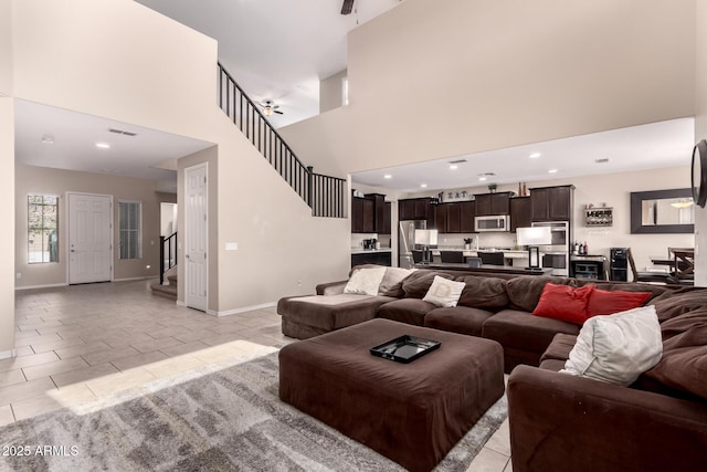 living room with light tile patterned floors, visible vents, stairs, and baseboards