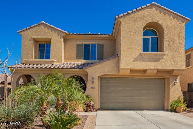 mediterranean / spanish-style house with a garage, driveway, a tile roof, and stucco siding