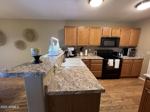 19943 N 77th Ave, Glendale, AZ 85308 - kitchen with black appliances, light wood-style flooring, a peninsula, and light countertops