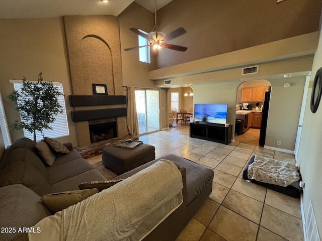 19943 N 77th Ave, Glendale, AZ 85308 - living area with arched walkways, ceiling fan, light tile patterned floors, a large fireplace, and a towering ceiling