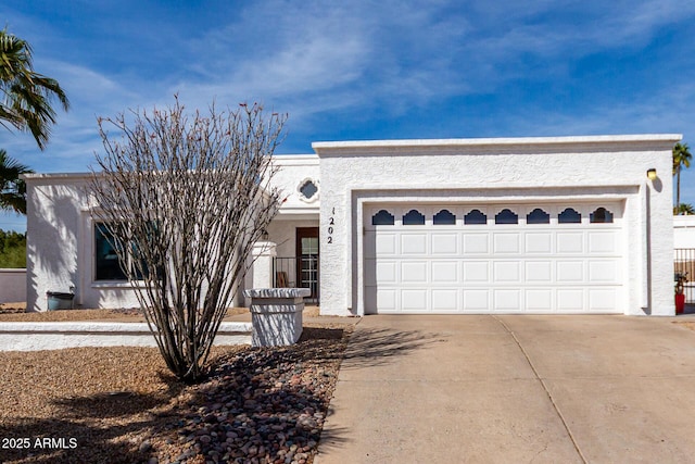 view of front of home with a garage, concrete driveway, and stucco siding