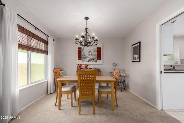 dining area featuring light colored carpet, a notable chandelier, and baseboards