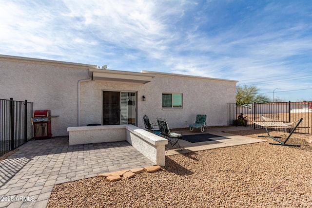 rear view of property featuring stucco siding, a patio, and fence