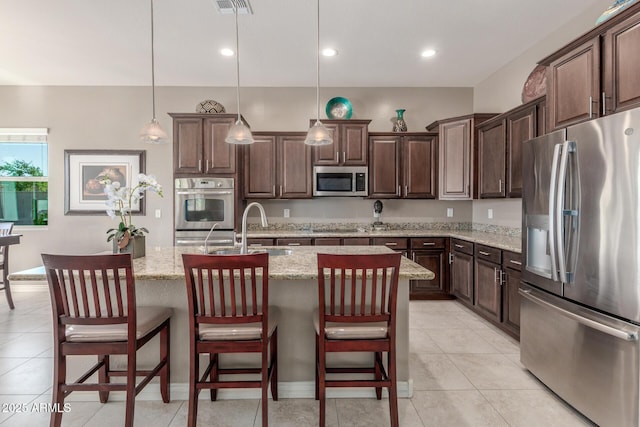 kitchen with stainless steel appliances, a sink, dark brown cabinets, light stone counters, and recessed lighting