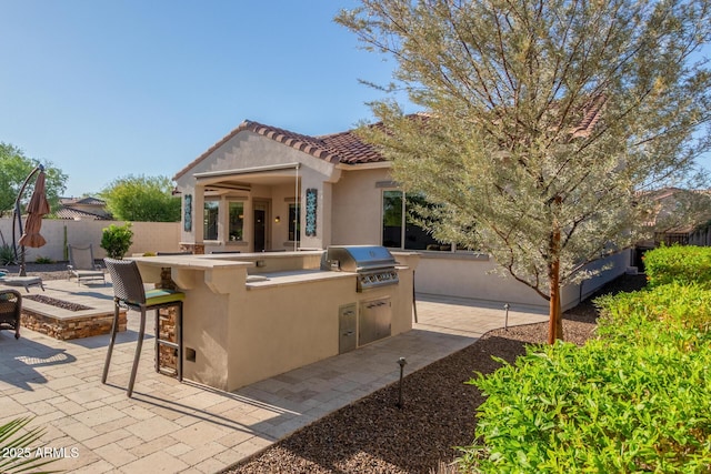 view of front facade with area for grilling, stucco siding, a patio area, fence, and a fire pit