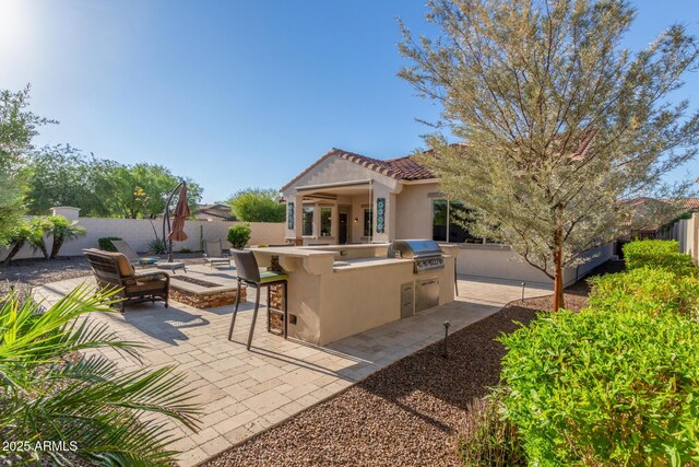 rear view of house with area for grilling, stucco siding, a fenced backyard, a patio, and an outdoor fire pit