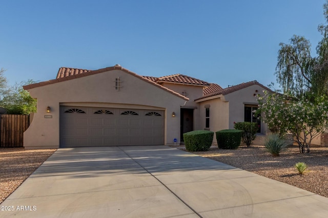 mediterranean / spanish-style house featuring an attached garage, a tiled roof, stucco siding, and driveway
