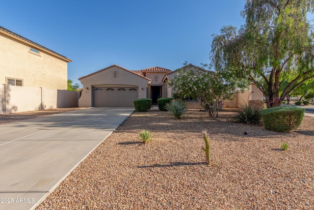 mediterranean / spanish-style home with concrete driveway, stucco siding, an attached garage, fence, and a tiled roof