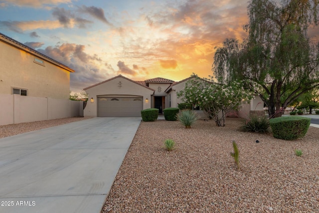 mediterranean / spanish home featuring driveway, fence, an attached garage, stucco siding, and a tile roof