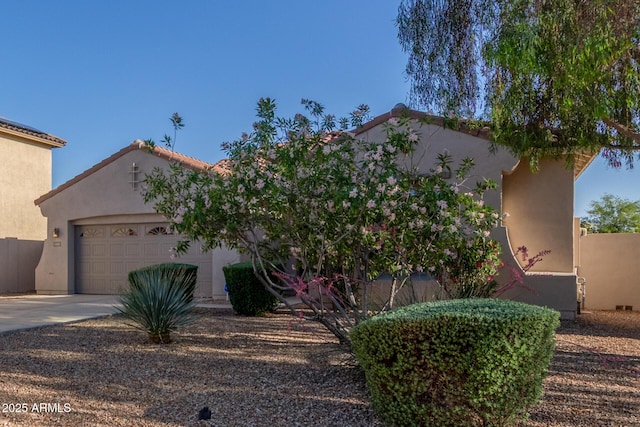 mediterranean / spanish home with concrete driveway, stucco siding, a garage, and a tiled roof
